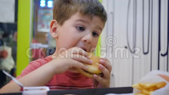 小男孩在儿童餐厅吃饭时胃口大开漂亮的宝宝在吃饭孩子在桌子上玩有害的食物视频的预览图