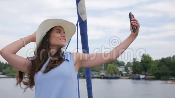 女性在背景海洋中创作自拍照片旅游视频漂亮女孩在游艇上自拍手中有Android视频的预览图