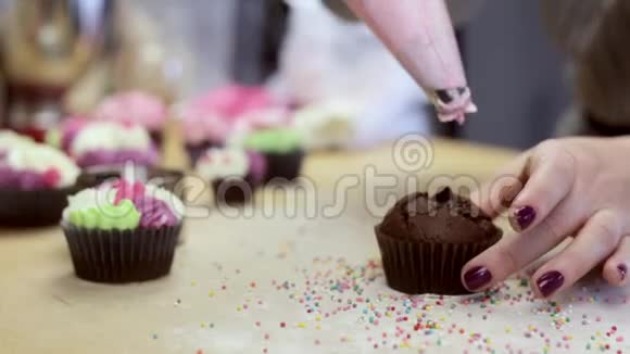 近距离观看女性手装饰巧克力蛋糕或松饼与粉红色奶油从糕点袋视频的预览图