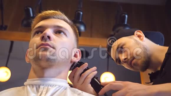 男理发师在理发店用剪刀剪男客户的头发口渴的过程慢动作关闭视频的预览图