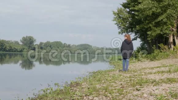 可爱的少女在河岸上钓鱼站在沙滩上拿着鱼竿视频的预览图