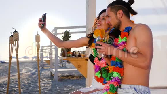 一对戴着花圈的情侣在小玩意上拍照来自一个异国情调的度假胜地的自拍男女视频的预览图