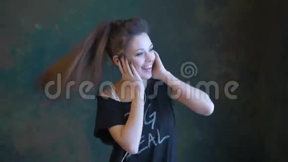 一个美丽的年轻女孩随着音乐跳舞使用耳机快速活力的舞蹈视频的预览图