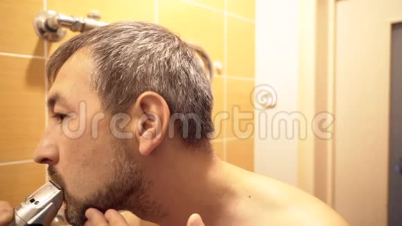 镜子前的浴室里的人用修剪器剪了胡子视频的预览图