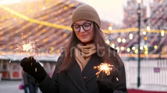 户外的年轻美丽快乐的微笑女孩抱着火花走在街上模特抬头穿着时髦视频的预览图
