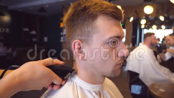 男理发师在理发店用剪刀剪男客户的头发口渴的过程慢动作关闭视频的预览图