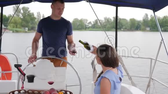 女人从瓶酒里倒出来在水上休息一对夫妇在游艇上喝酒浪漫的夫妇喝红饮料视频的预览图