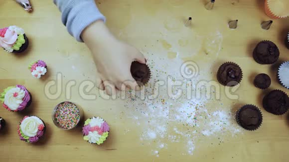 顶部的年轻女性手装饰巧克力蛋糕或松饼与奶油使用糕点袋为此视频的预览图