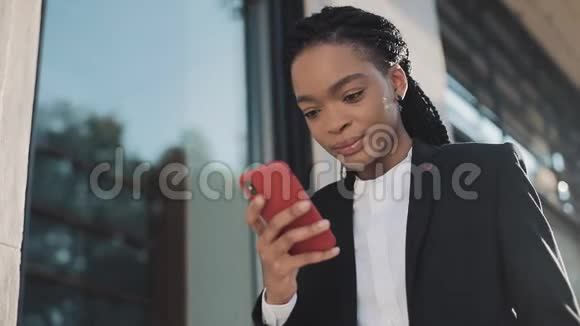 时尚的非洲女商人使用智能手机站在商业中心附近的街道上黑色时尚可怕的家伙非洲裔视频的预览图