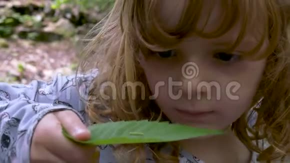 一只小姑娘抱着的叶子上的绿色毛毛虫视频的预览图
