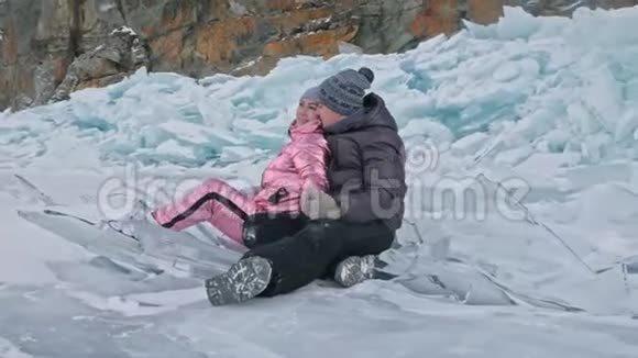 在冰封的湖面上年轻夫妇在冬天散步时玩得很开心恋人们坐在冰上亲吻和拥抱青年视频的预览图