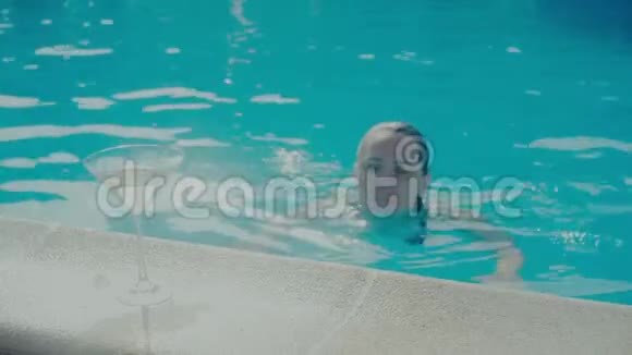 美丽的女人在游泳池附近享受假期带着一杯马提尼视频的预览图