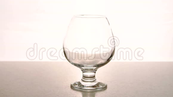 在一个空杯子里瓶子里的酒精倒在白色的背景上视频的预览图