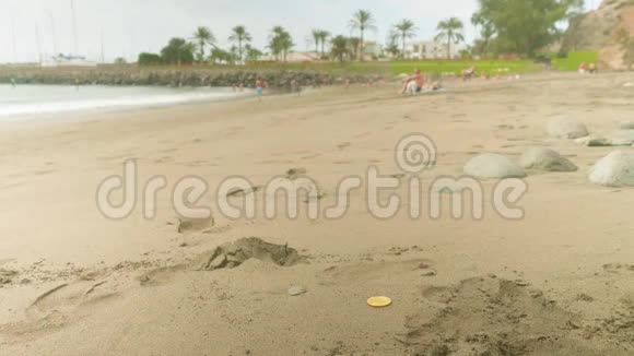 缩小比特币躺在沙滩上模糊的人在海滩上的背景视频的预览图