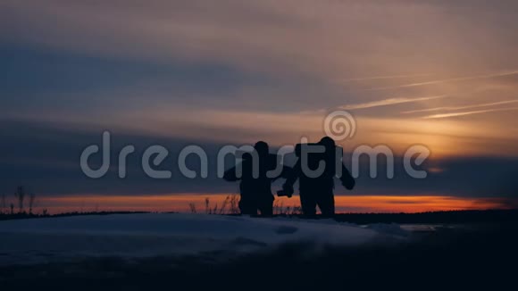 两名游客在日落剪影和秋天有趣的积极自然景观冬季雪两名男性摄影师视频的预览图