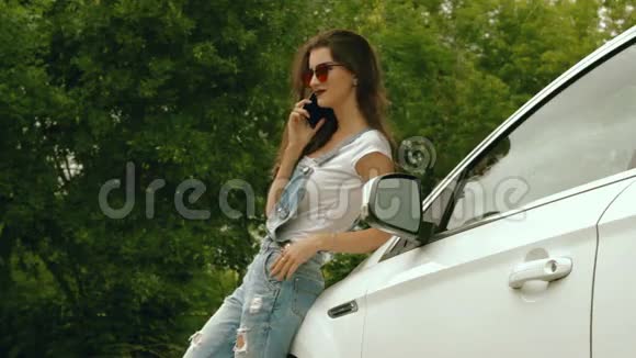 穿牛仔裤的女孩站在机器附近用电话说话视频的预览图