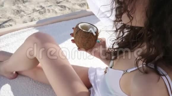 美丽的女孩在海边打招呼在度假胜地避暑女人喝椰子鸡尾酒视频的预览图