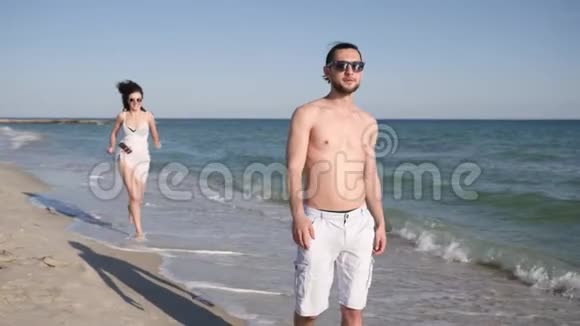 情侣在沙滩上拍自拍男人围着女孩转积极的年轻人从假期旅行中拍摄视频视频的预览图