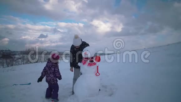 妇女和儿童一起在山上雕刻一个雪人视频的预览图