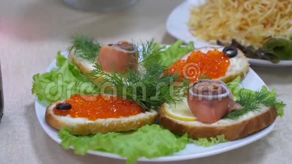 三明治里有红鱼和红鱼子酱盘子里还有沙拉节日餐桌美味的食物视频的预览图