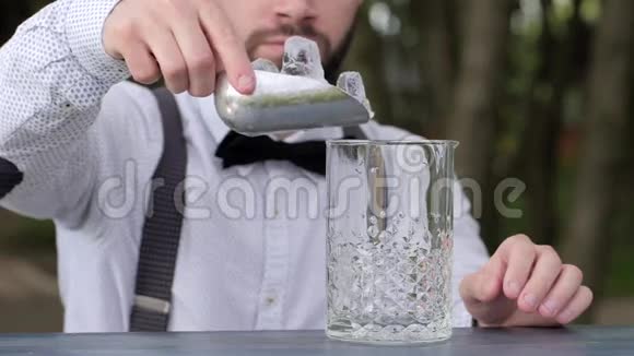酒吧老板把冰块放进玻璃杯里放酒精酒吧老板把冰块放进柜台的玻璃杯里视频的预览图