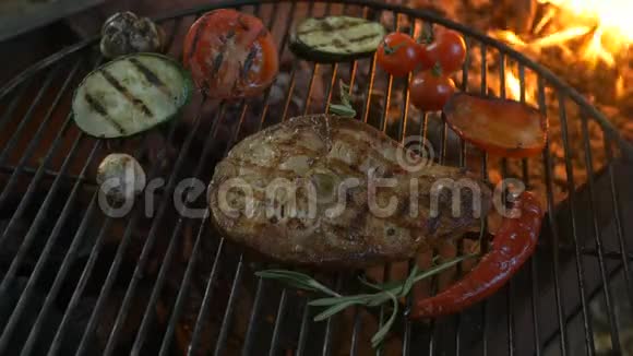 蔬菜和鱼烤架牛排鱼厨师在夏季餐厅露台的圆形烤架上用铁钳转动视频的预览图