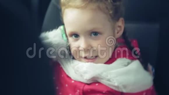 快乐的女孩坐在汽车的后座上打着电话视频的预览图