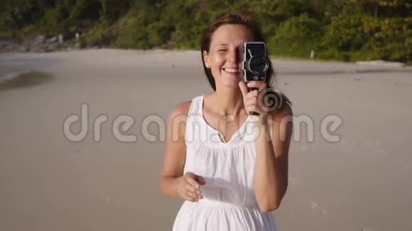 年轻女子在海滩上使用老式相机的肖像视频的预览图