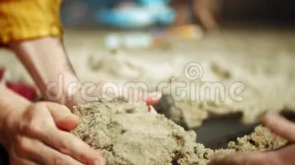 小女孩在沙滩上玩沙子手的特写视频的预览图
