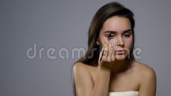 一个漂亮的年轻女子梳着眉毛美丽的女人用化妆刷画出眉毛的美丽形状关门视频的预览图