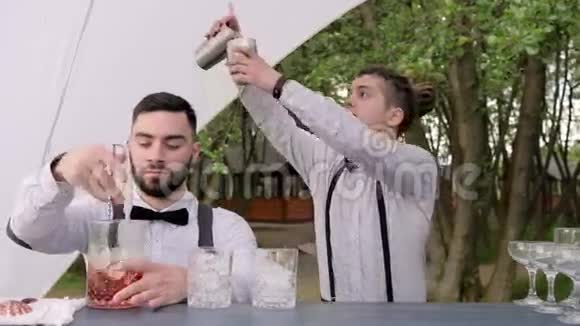 酒吧后面有两个调酒师酒保在杯子里搅拌一勺冰酒保把鸡尾酒从摇床倒入搅拌杯中视频的预览图