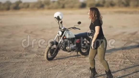 年轻漂亮的女人在日落或日出时在沙漠里跳舞背景摩托车视频的预览图