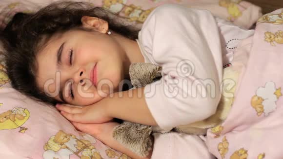 女孩穿着睡衣睡觉抱着一个柔软的玩具在梦中刮鼻子视频的预览图