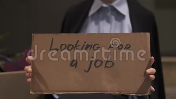 悲伤的女商人拿着纸板坐在街上寻找工作标志视频的预览图