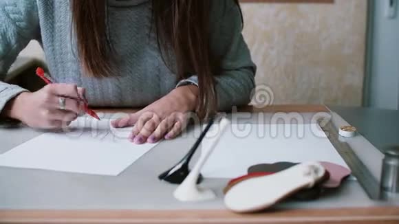 女人拿着铅笔坐在桌子旁在纸上画素描在轮廓上擦除左滑前视4K视频的预览图