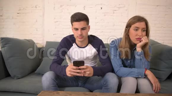 利用手机上的社交媒体对年轻男子进行狂轰滥炸无视女朋友在家沙发沙发上的感受这位女子很沮丧视频的预览图