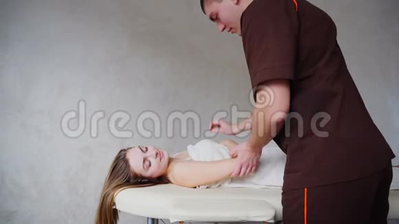 经验丰富的男性医学专家动作温和为躺在沙发上的男女病人做手部按摩视频的预览图