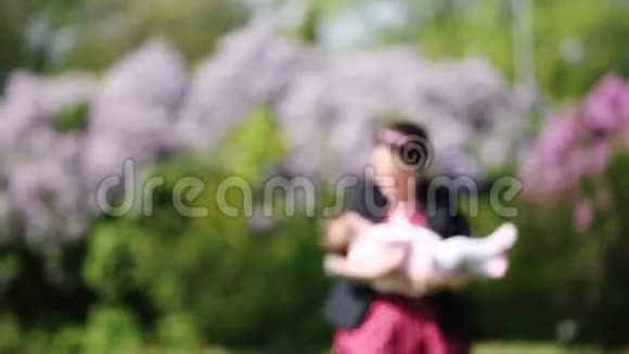 快乐的母亲和可爱的女婴在公园里和美丽的花朵一起玩耍视频的预览图