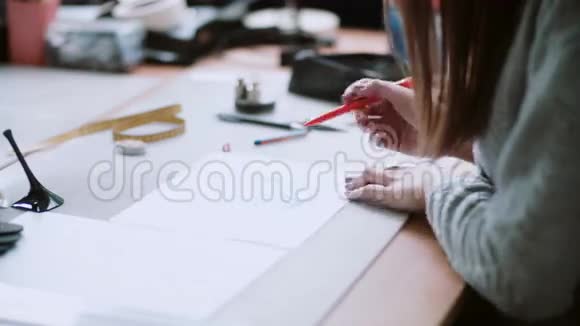 年轻设计师坐在桌子旁画蓝鞋的素描女人在纸上擦掉侧视4K视频的预览图