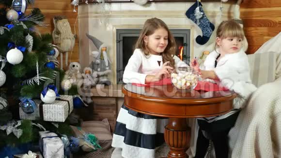 两个女孩姐姐给圣诞老人写信和画画女孩坐在壁炉旁孩子在房子附近视频的预览图
