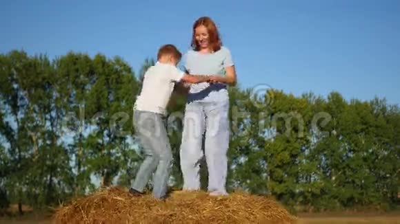 一个女孩带着孩子在干草堆上玩耍视频的预览图