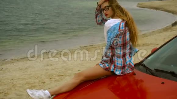 热辣的年轻女人坐在红车上吃棒棒糖视频的预览图
