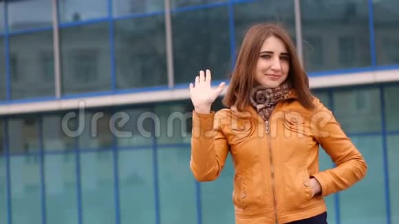 美丽的年轻女子问候挥手在城市户外视频的预览图