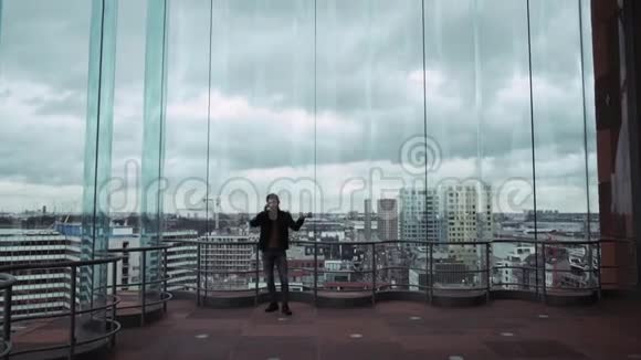 一个人从摩天大楼俯瞰城市天际线剪影在电话上交谈然后跳舞在一个视频的预览图