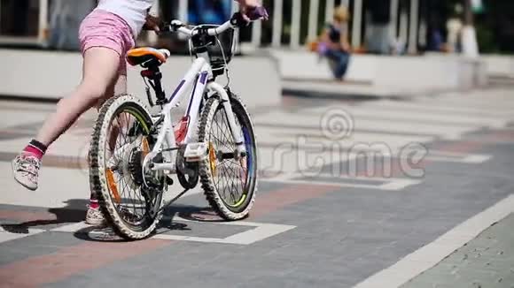 在阳光明媚的日子里夏天公园里骑自行车的小女孩的后视镜视频的预览图