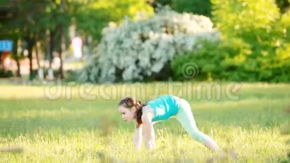 活泼的小女孩在夏天公园的草地上做一个手推车视频的预览图