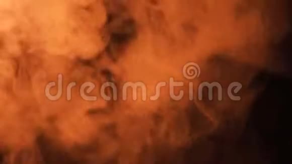 在黑色背景上喷出的橙色烟雾被火照亮视频的预览图