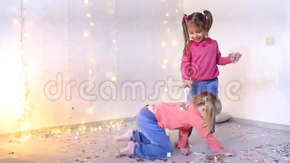 两个女孩在客厅里玩耍从地板上捡起圣诞纸屑视频的预览图