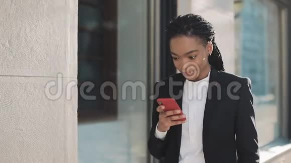 时尚的非洲女商人使用智能手机站在商业中心附近的街道上黑色时尚恐惧症视频的预览图