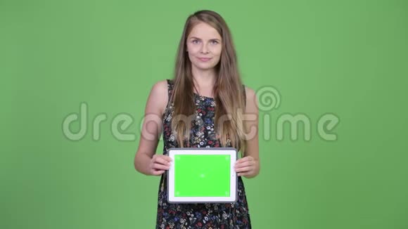 年轻快乐的孕妇展示数码平板电脑视频的预览图